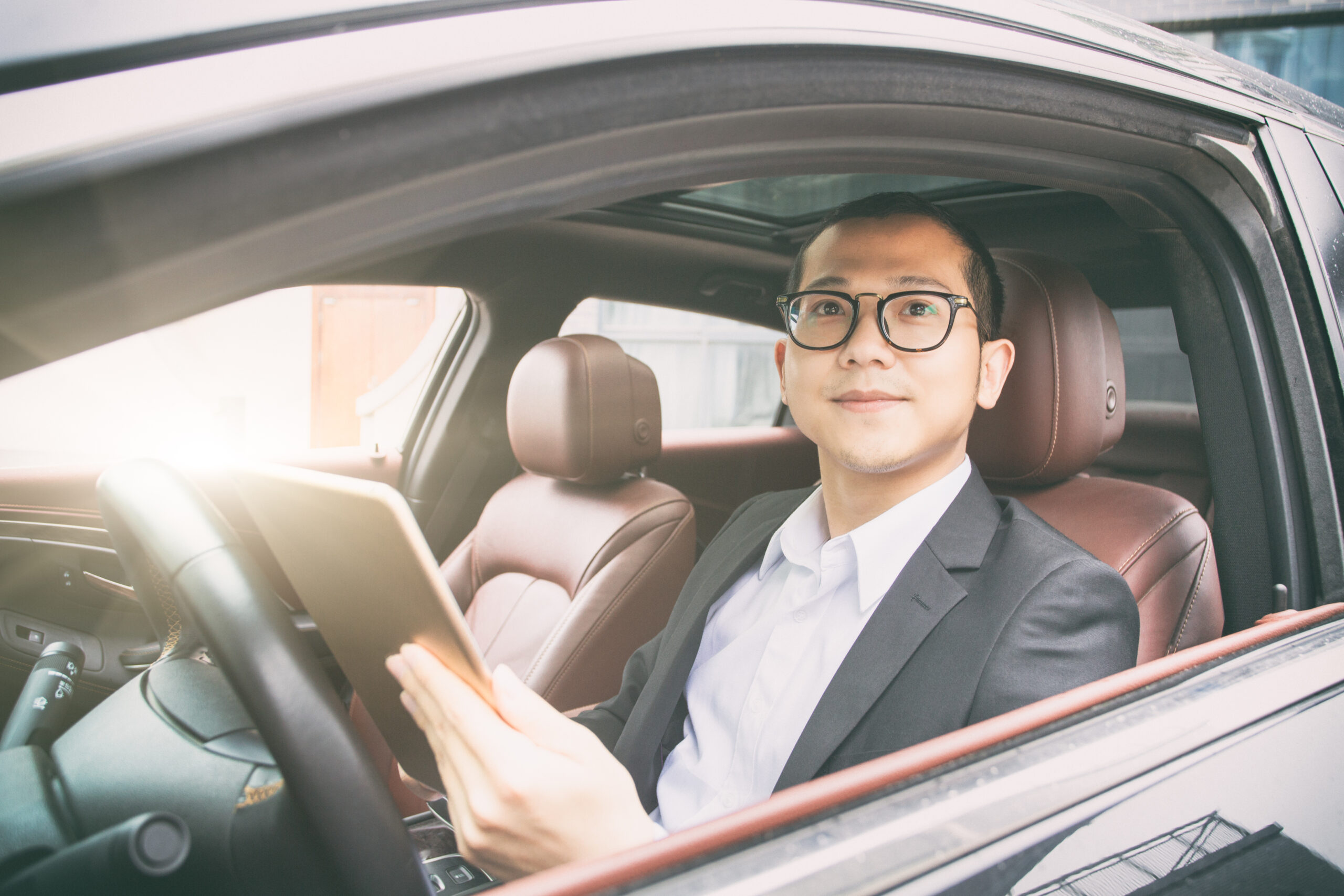 Businessman sit in his car using digital tablet.